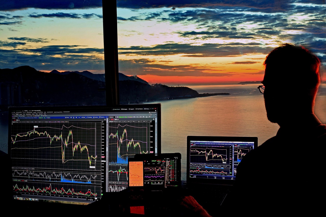 Professional trader working with multiple screens against sunset backdrop